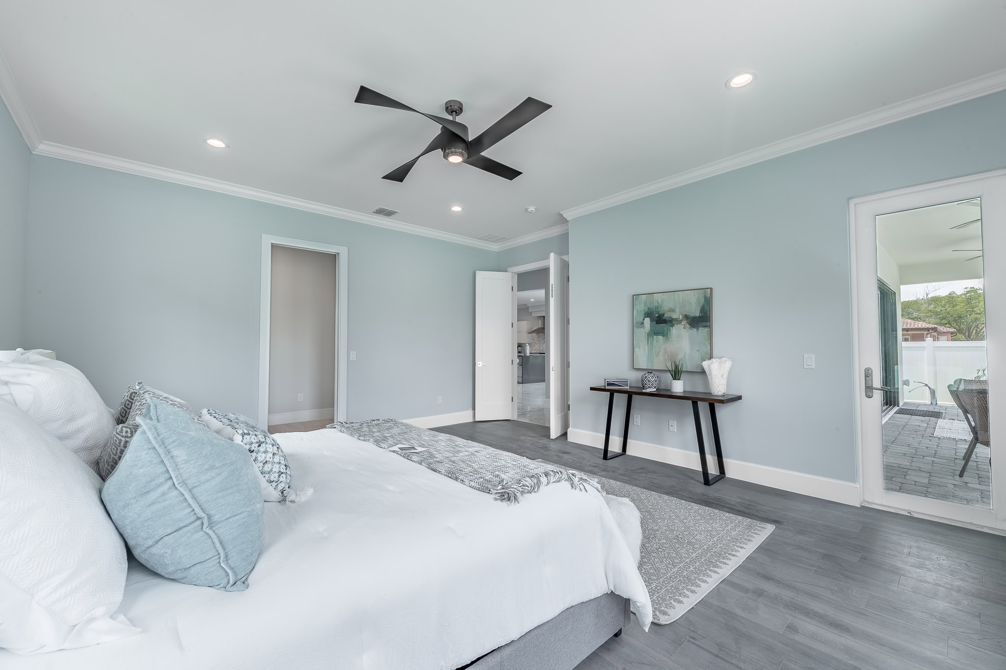 Primary bedroom in a Queen Homes custom-built home in Orlando, FL, with ceiling fan and private patio access